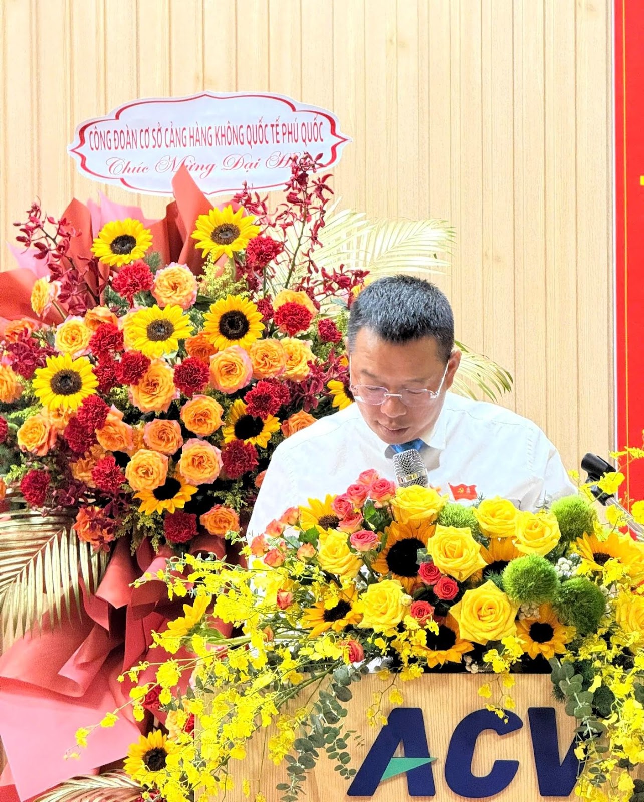 A person standing behind a podium with flowersAI-generated content may be incorrect.