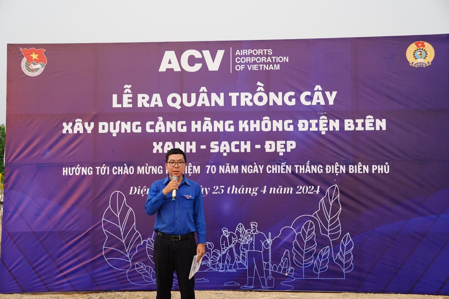 A person standing in front of a bannerDescription automatically generated
